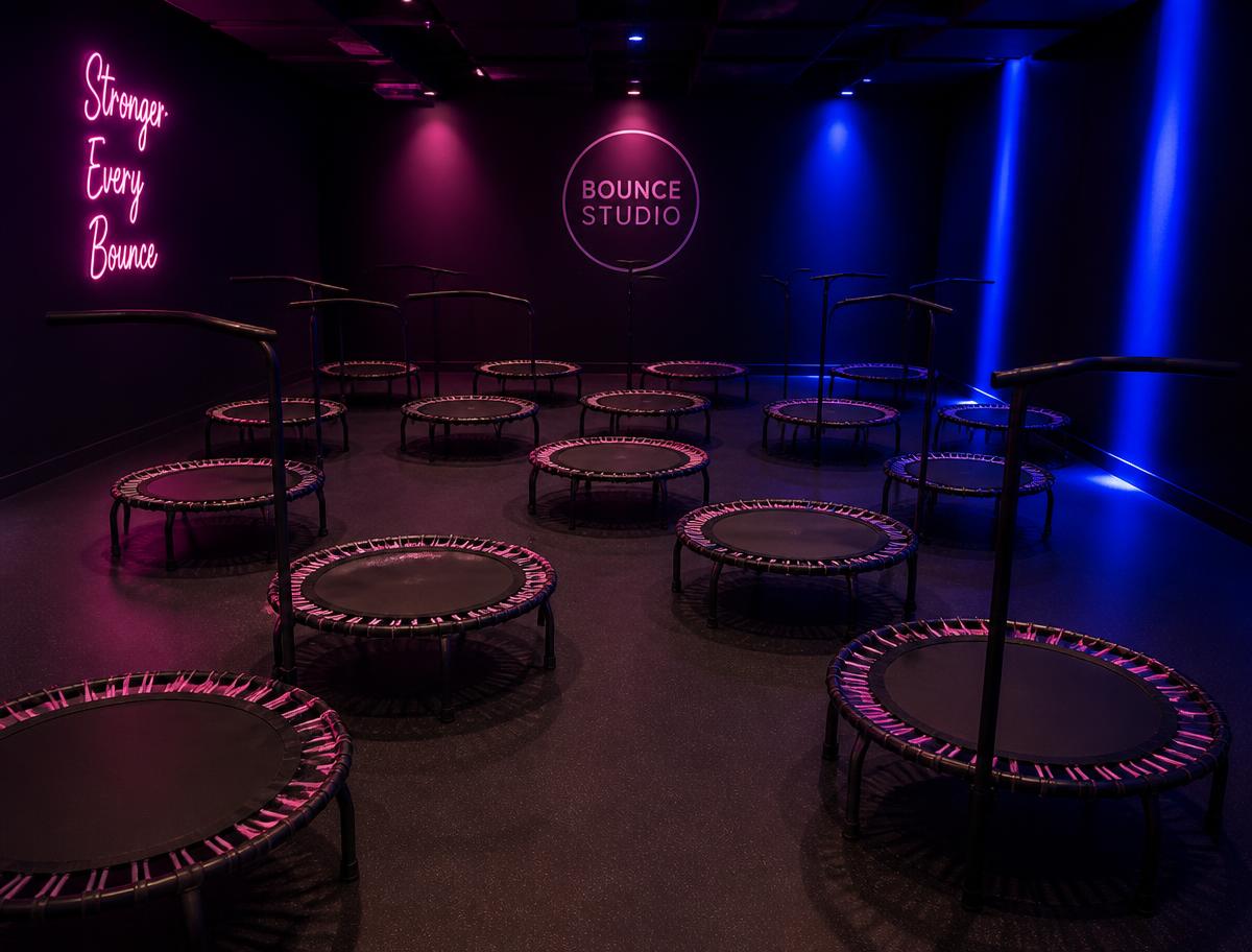 Rebounding studio lit with glow lights, rows of mini trampolines ready for class